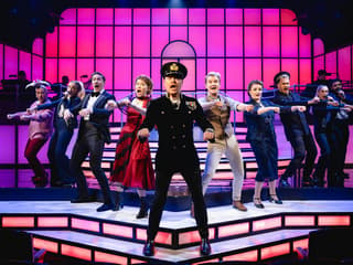 Cast performing a musical number in Titanique Westend with vibrant stage lighting