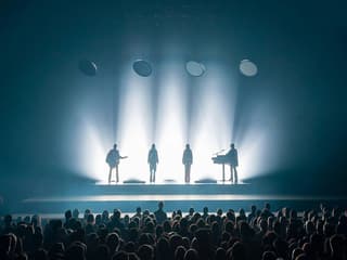 Silhouetted performers on stage with audience at ABBA Voyage show in London