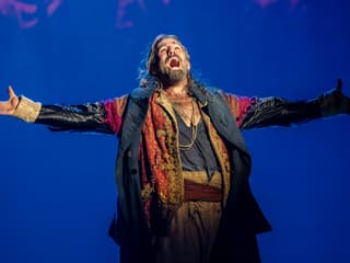 Performer in costume on stage during Oliver production