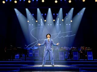 Performer on stage during Sinatra The Musical, Westend, with band and signature backdrop