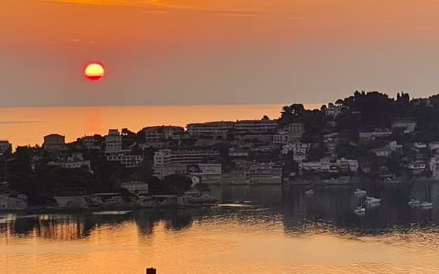 Sunset over the Monaco coastline on the French Riviera, the sun low over the sea and hillside town