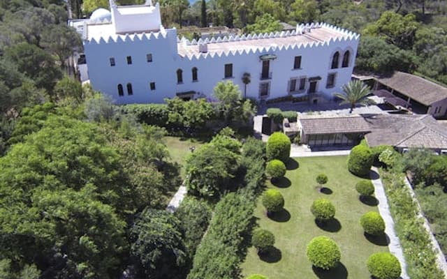 Aerial view of the white Sa Bassa Blanca mansion and gardens overlooking the sea in Alcudia, Mallorca