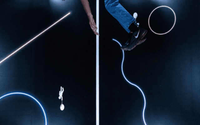 Visitor in an upside-down optical illusion exhibit with neon light trails at a Las Vegas museum