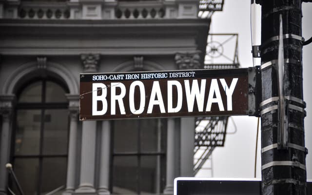 Brown Broadway street sign in front of a cast-iron building in SoHo, New York