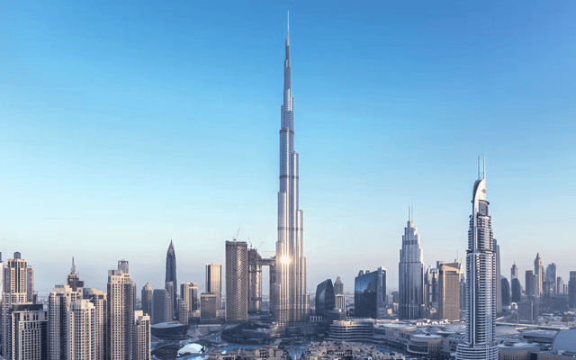 The Dubai skyline against a bright blue sky with the towering Burj Khalifa in the center of the photo.