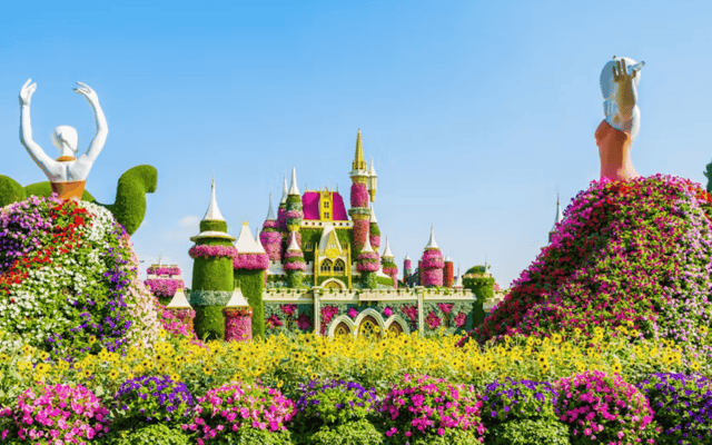 Topiary castle and flower-covered dancer figures among masses of blooms at Dubai Miracle Garden