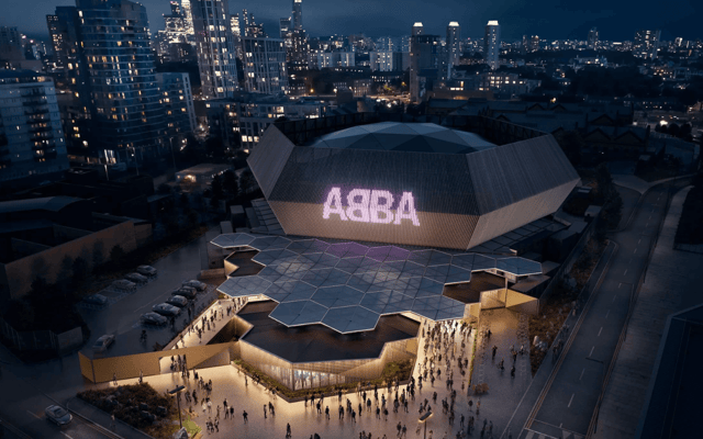ABBA Arena dome lit with the pink ABBA logo at night with crowds outside in London