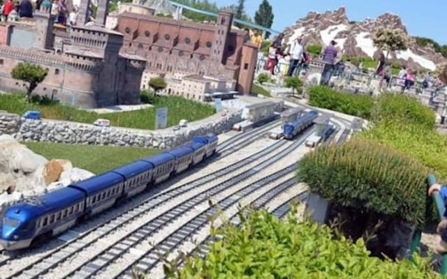 Model trains and a miniature castle with visitors at a miniature park in Rimini, Italy