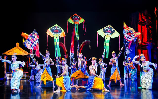 Balinese cultural dancers in bright costumes with kite props on a stage in Bali