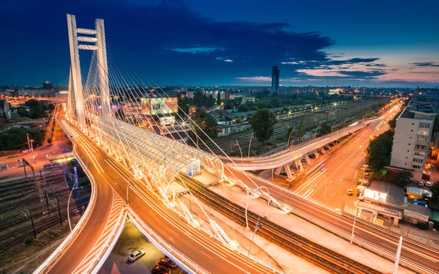 Basarab Overpass cable-stayed bridge lit up at night over the Bucharest cityscape with light trails