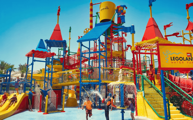 Colourful play structure and water slides with children splashing at LEGOLAND Water Park Dubai