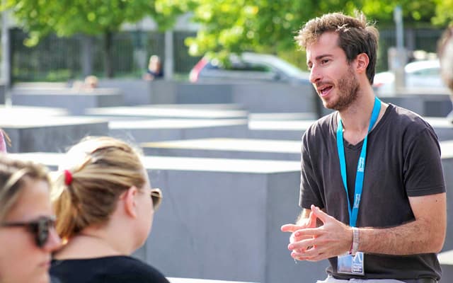 Walking tour guide talking to visitors at the Holocaust Memorial slabs in Berlin