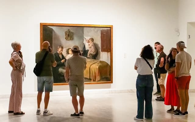 Visitors viewing a large painting in a bright white-walled Barcelona art museum