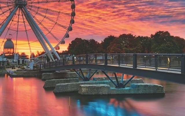 La Grande Roue ferris wheel and footbridge reflected in the water at sunset in Montreal