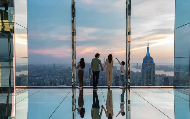 Family on a glass-floor sky deck overlooking the Manhattan skyline at sunset