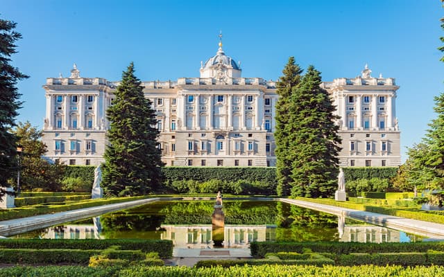 The Royal Palace of Madrid behind the formal Sabatini Gardens under a clear blue sky
