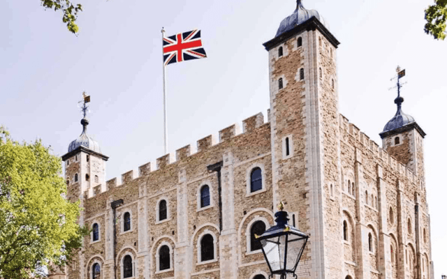 The White Tower at the Tower of London with the Union Jack flag under a blue sky
