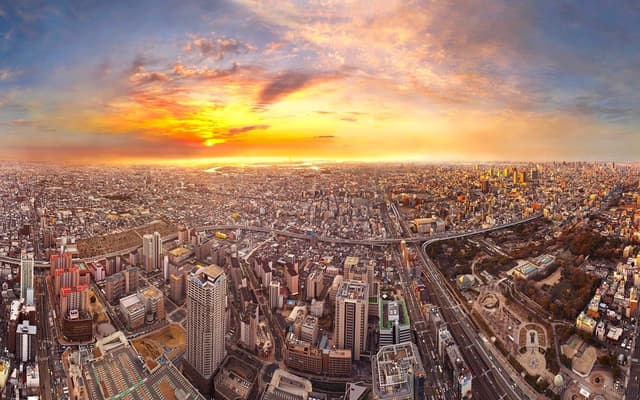 Aerial panorama of the Osaka skyline at sunset with an orange sky over the city