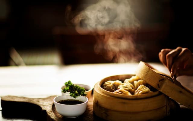 Steaming bamboo basket of dumplings with dipping sauce, New York winter dining