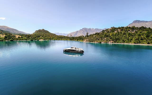 Sleek cruise boat on the blue waters of Lake Wakatipu framed by mountains near Queenstown, New Zealand