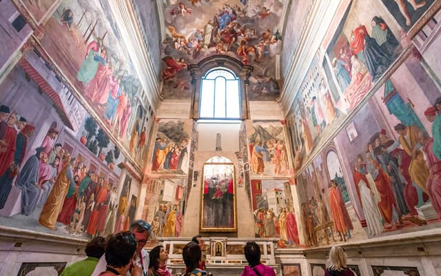 Visitors admiring Renaissance frescoes on the walls of a Florence chapel