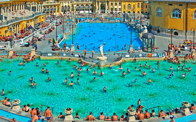 Bathers in the grand outdoor pools of Budapest's Szechenyi Thermal Baths by the yellow palace