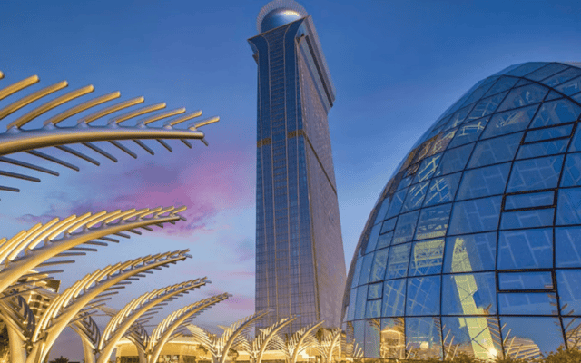 The View at Palm Jumeirah tower and glass dome at dusk in Dubai with lit palm sculptures