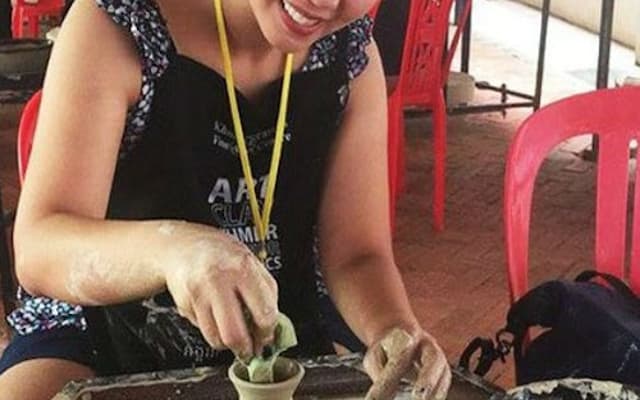 Smiling woman shaping a clay pot at a pottery wheel in a workshop in Siem Reap