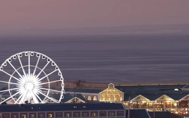 Cape Town V&A Waterfront at dusk with the illuminated Cape Wheel and harbour