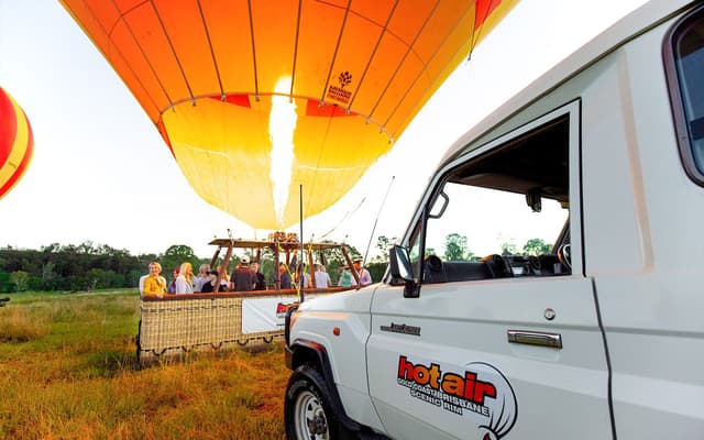 Hot air balloon inflating at sunrise with passengers in the basket near Brisbane