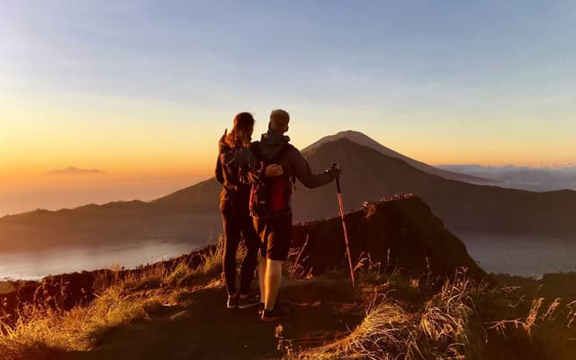Couple watching the sunrise from the summit of Mount Batur volcano in Bali