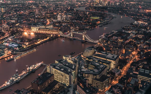 Aerial night view of London with the lit Thames, Tower Bridge and glowing city skyline