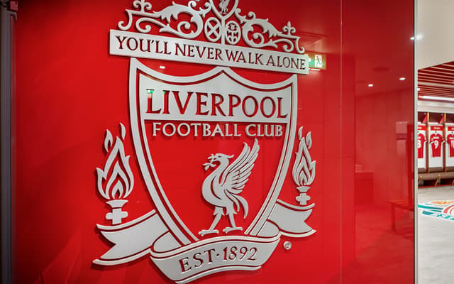 Liverpool FC crest and You'll Never Walk Alone motto on a red dressing-room wall at Anfield