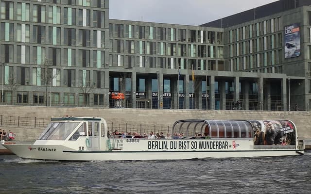 White river cruise boat on Berlin's Spree river with modern glass buildings behind