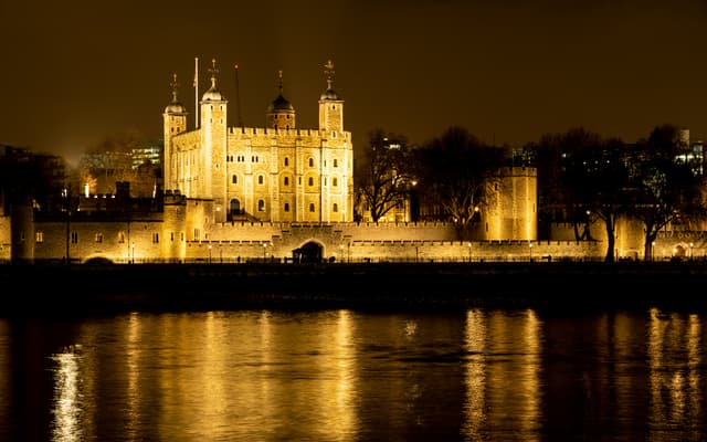 Tower of London floodlit at night reflected in the River Thames