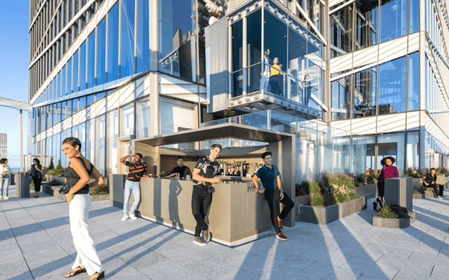Outdoor terrace bar at Summit One Vanderbilt with guests and the glass tower above in New York