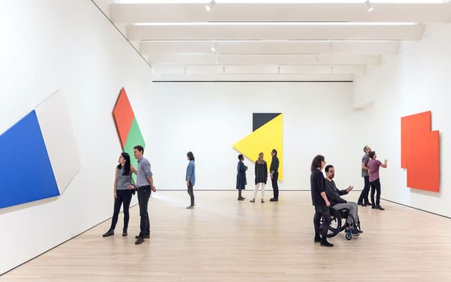 Visitors viewing bold geometric colour-block paintings in a bright San Francisco art gallery