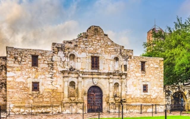 The historic Alamo limestone mission facade under a blue sky in San Antonio