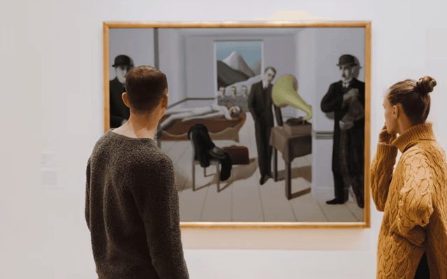 Two visitors viewing a framed Surrealist painting at MoMA modern art museum in New York