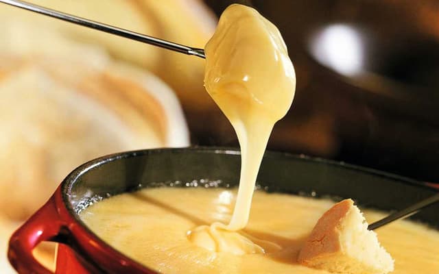 Bread dipped into a pot of melted Swiss cheese fondue