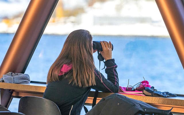 Traveller photographing the Arctic landscape on a Tromso fjord cruise