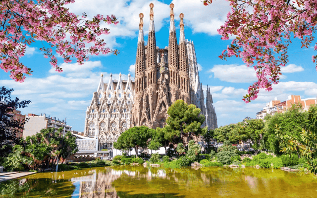 The completed Sagrada Família in Barcelona seen across the lake, framed by blossom