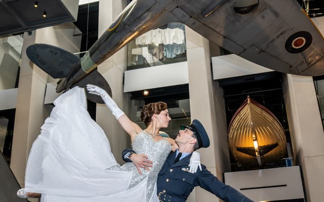 Katrina Lyndon and Reece Causton dancing beneath a Spitfire at IWM London in Matthew Bourne's Cinderella