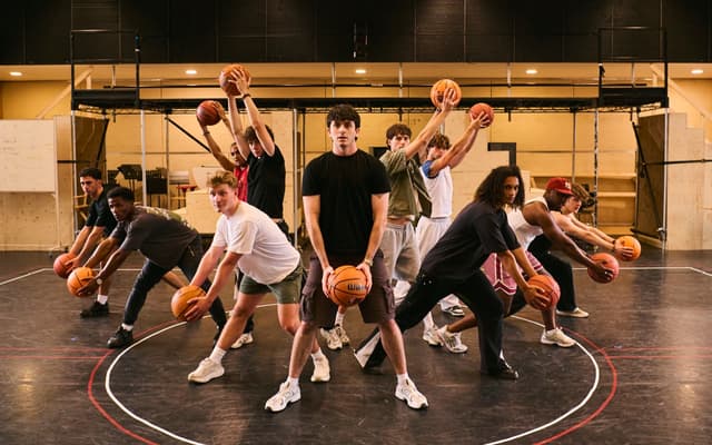Troy Bolton and the East High basketball team pose with basketballs in a High School Musical rehearsal