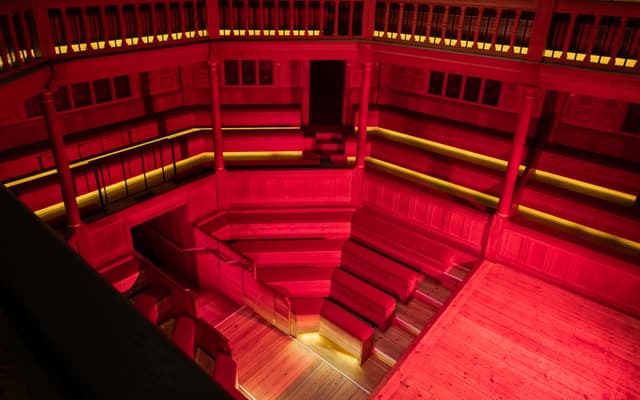 The candlelit Sam Wanamaker Playhouse bathed in red light, artwork for Julius Caesar