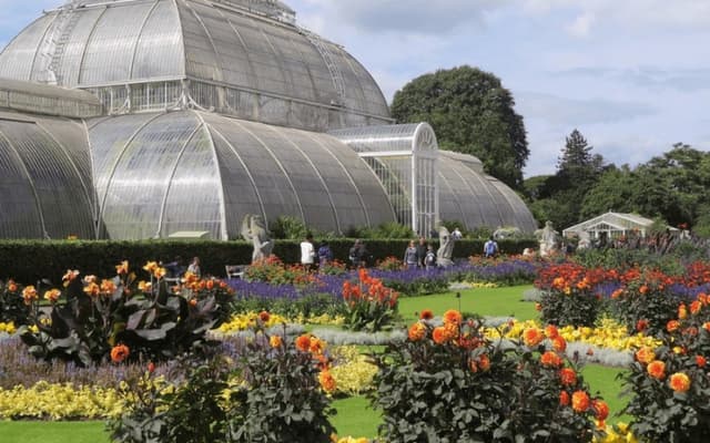 The Palm House at Kew Gardens with vibrant summer flowerbeds in front
