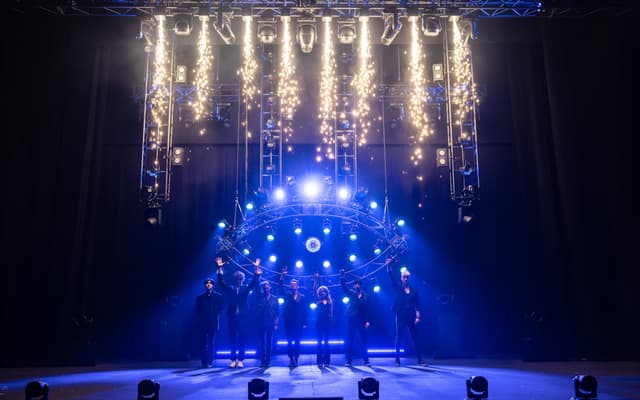 The company of Now You See Me Live on stage under pyrotechnics at the London Coliseum