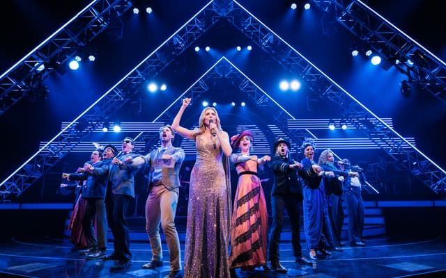 Céline Dion in a gold gown sings with the cast of Titanique on Broadway