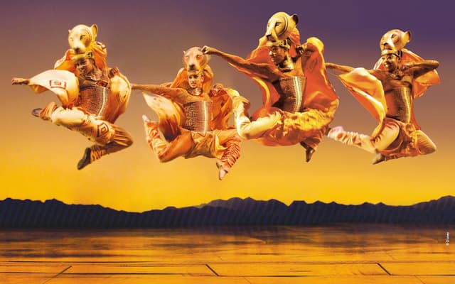 The ensemble of The Lion King leaping across the stage at the Lyceum Theatre