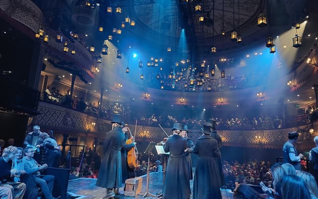 A full house at the Old Vic theatre in London during a performance, with lanterns hanging above the stage